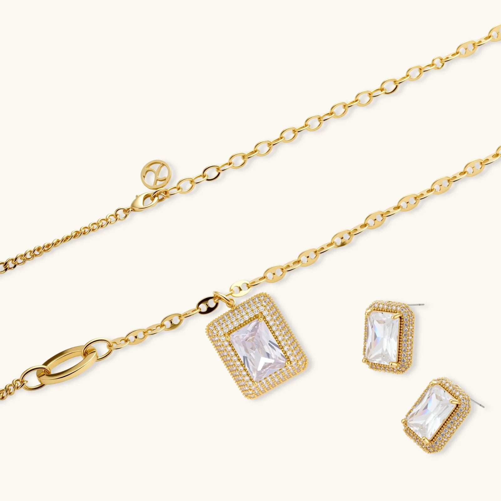 Gold-plated jewelry set with rectangular cubic zirconia stones in pave halo settings on cream background