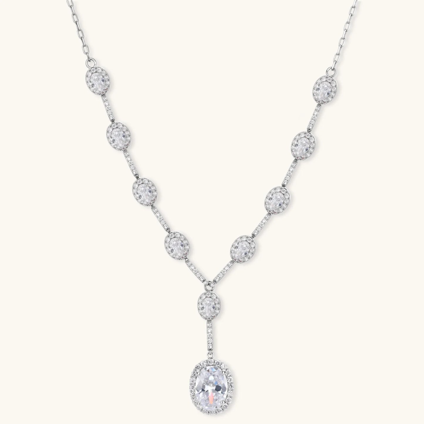 Elegant white gold plated jewelry set with oval cubic zirconia stones in halo settings, featuring Y-necklace and drop earrings.