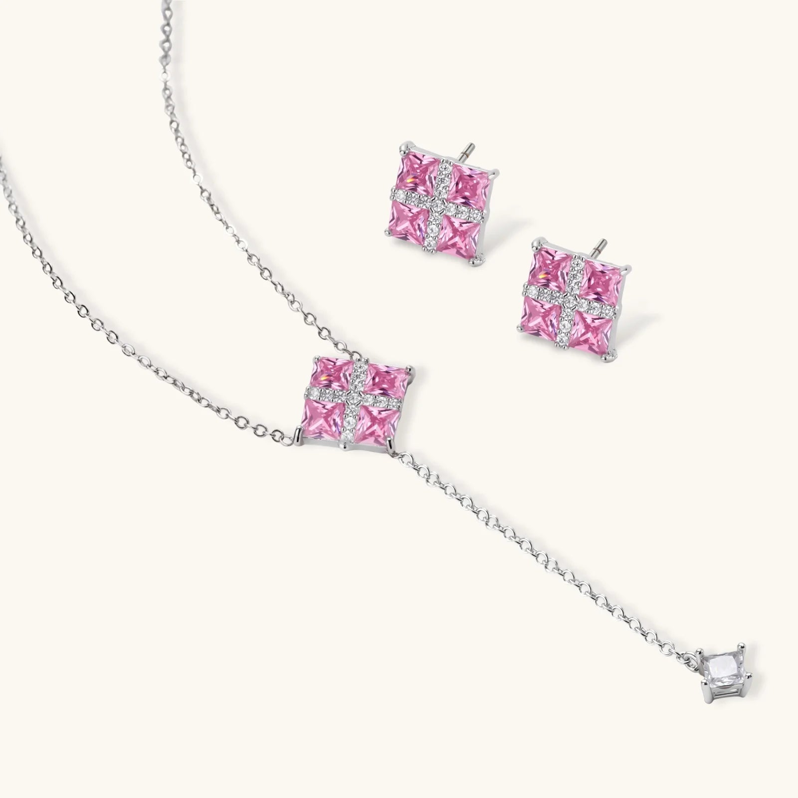 White gold plated jewelry set with pink cubic zirconia stones in geometric cross design, featuring Y-necklace and square stud earrings