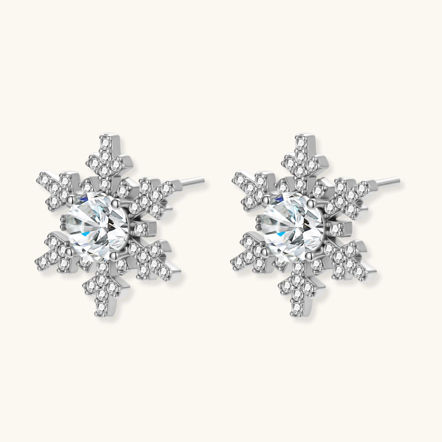 Sterling silver snowflake stud earrings with brilliant moissanite centers and intricate geometric patterns on cream background