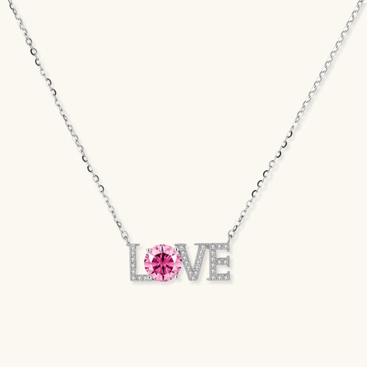 Sterling silver LOVE necklace with pink moissanite stone replacing the O, featuring crystal-set letters on delicate chain.