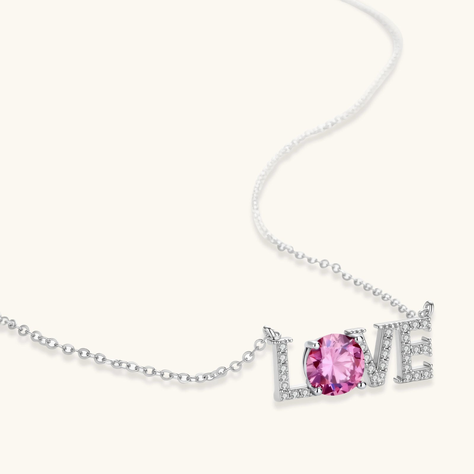 Sterling silver LOVE necklace with pink moissanite stone replacing the O, featuring crystal-set letters on delicate chain.