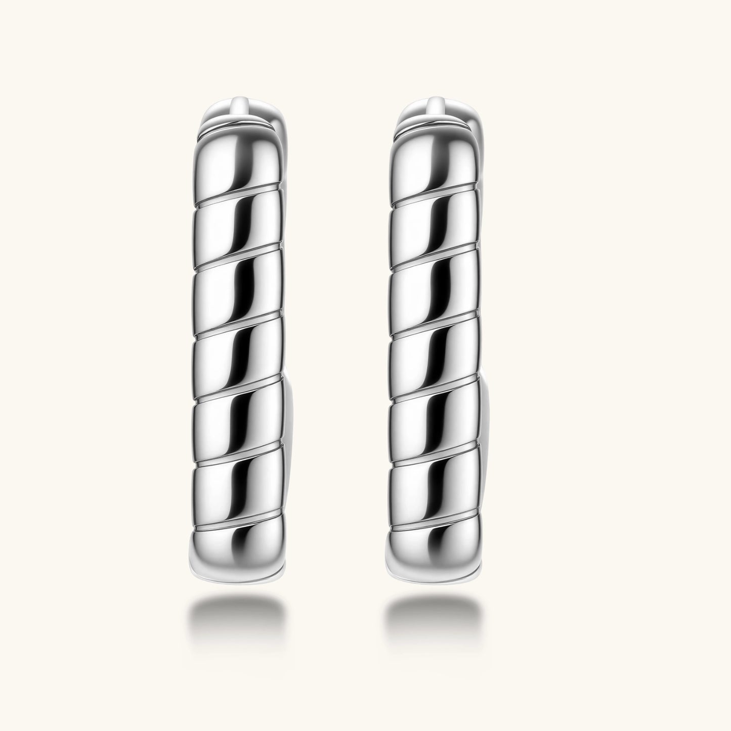 Close-up of platinum-plated sterling silver hoop earrings with horizontal textured grooves on white background.