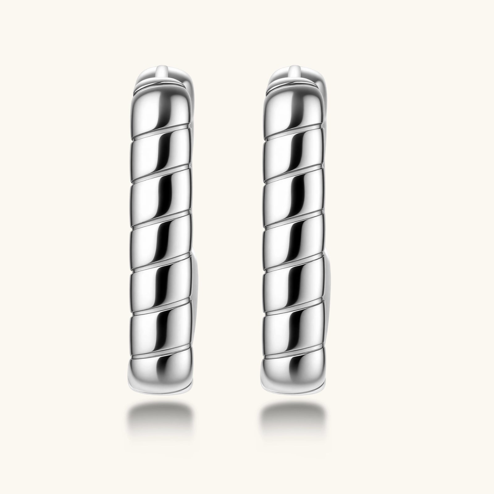 Close-up of platinum-plated sterling silver hoop earrings with horizontal textured grooves on white background.