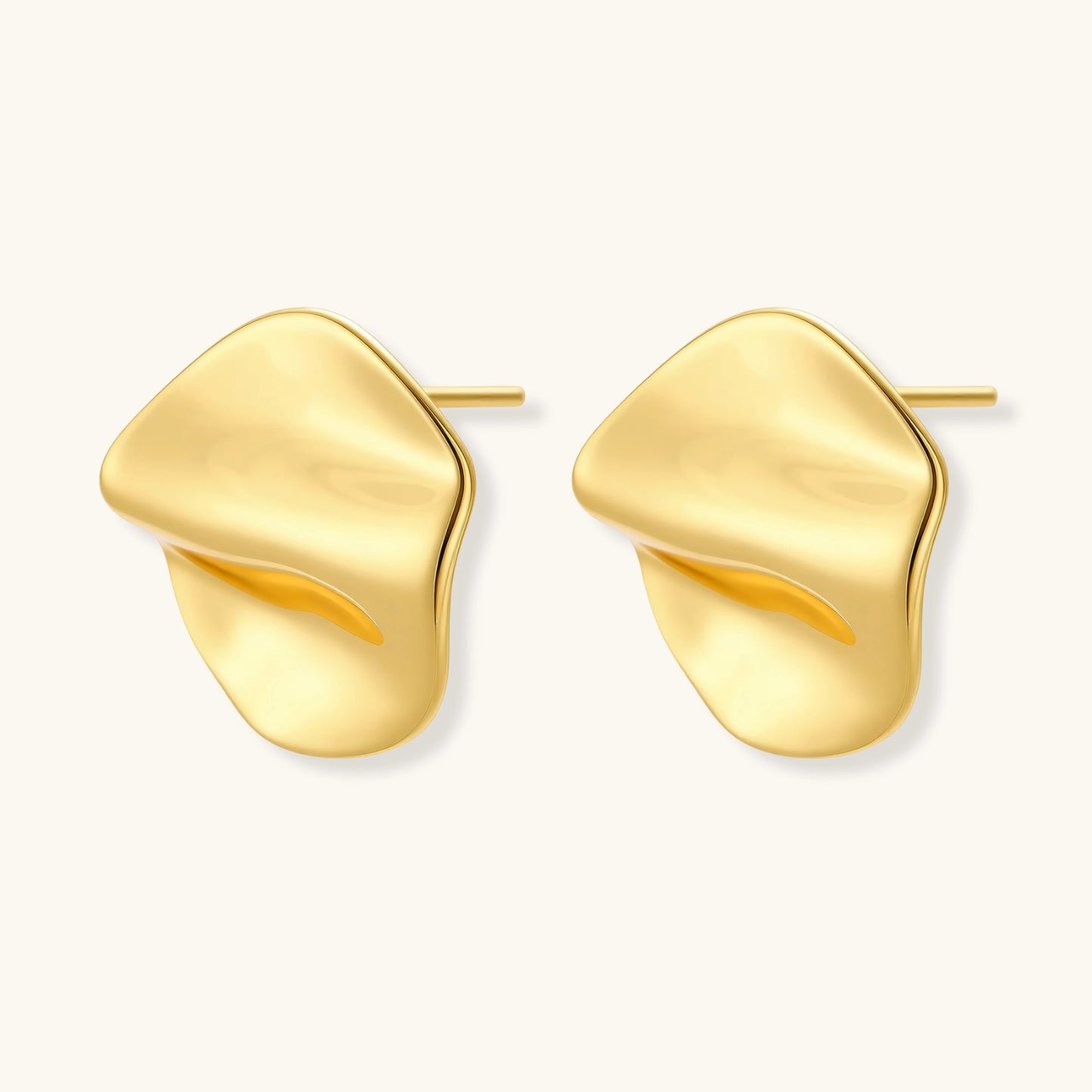 Close-up of organic gold-plated sterling silver stud earrings with flowing sculptural design and curved cut-outs