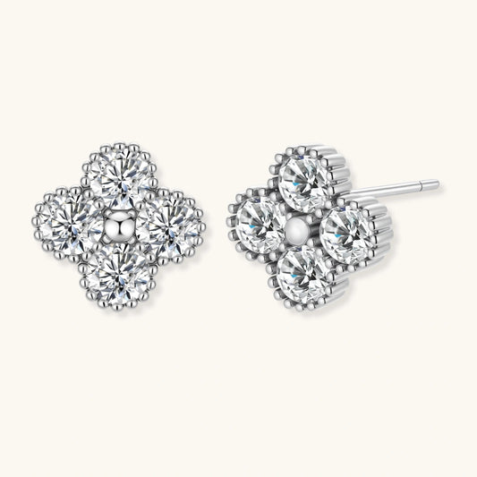 Dainty sterling silver quatrefoil stud earrings with four brilliant moissanite stones and center accent on white background.