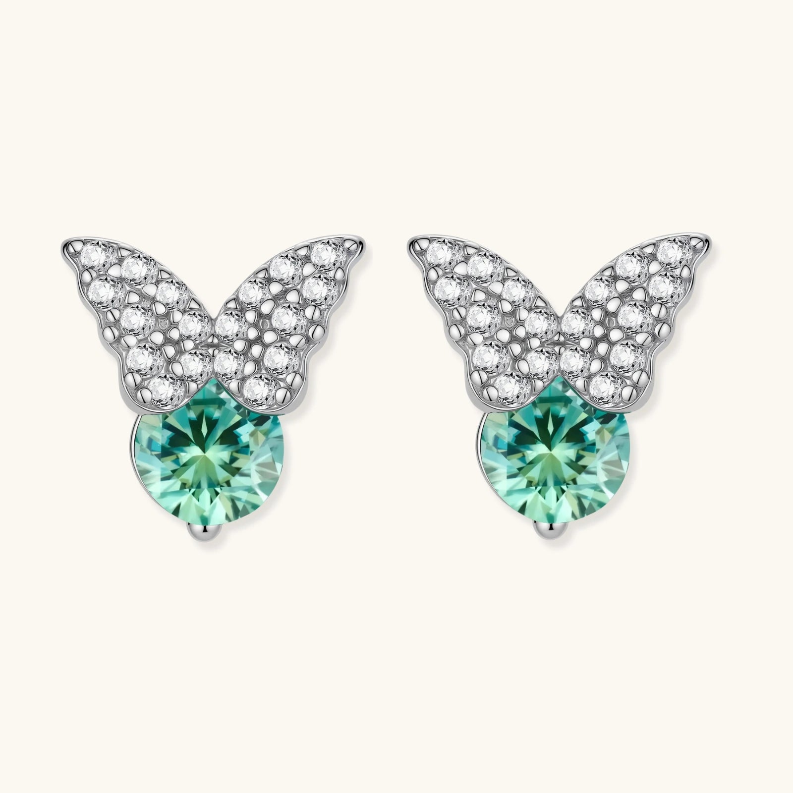 Sterling silver butterfly stud earrings with crystal wings and mint green center stones on cream background.