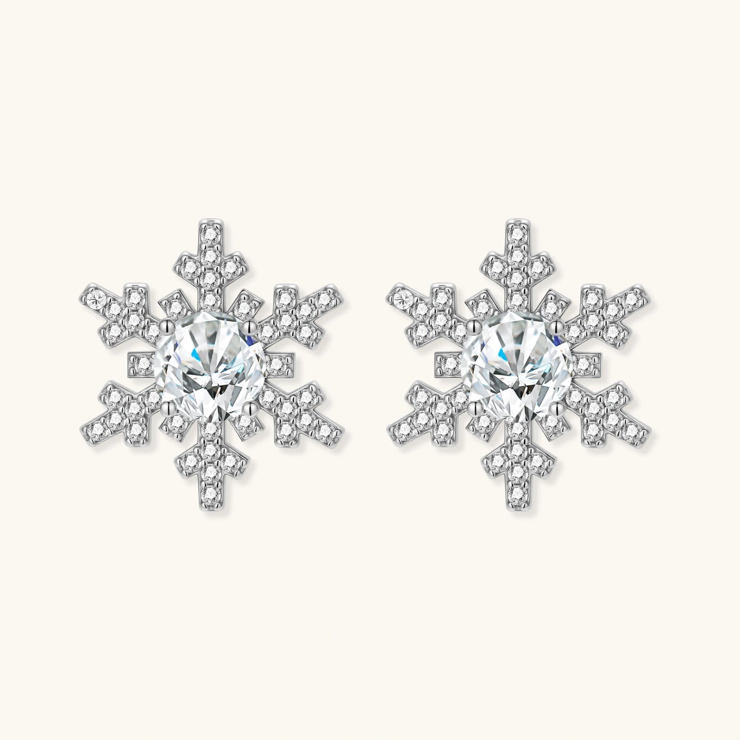 Sterling silver snowflake stud earrings with brilliant moissanite centers and intricate geometric patterns on cream background
