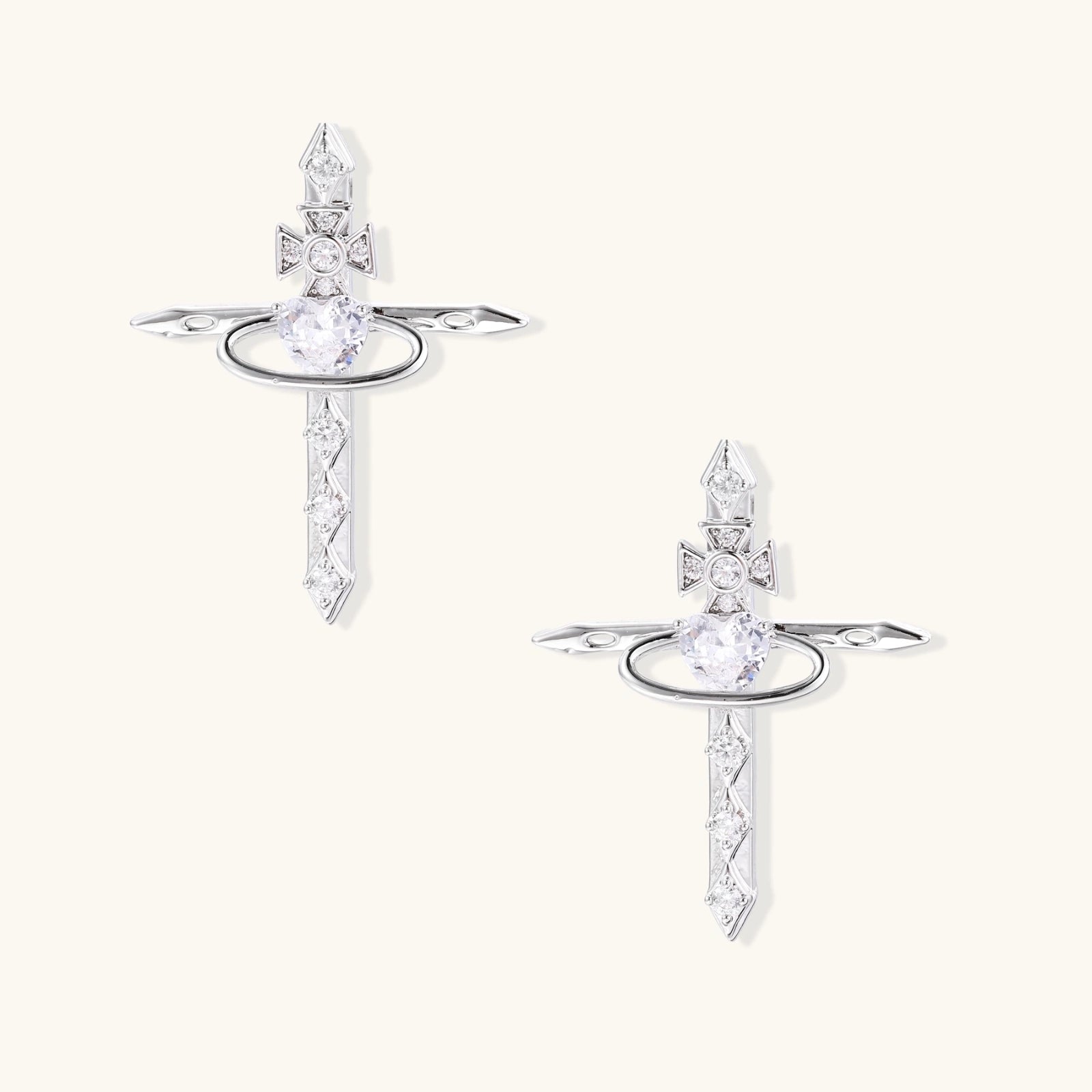White gold plated cross earrings with orbital ring & zirconia stones on cream background