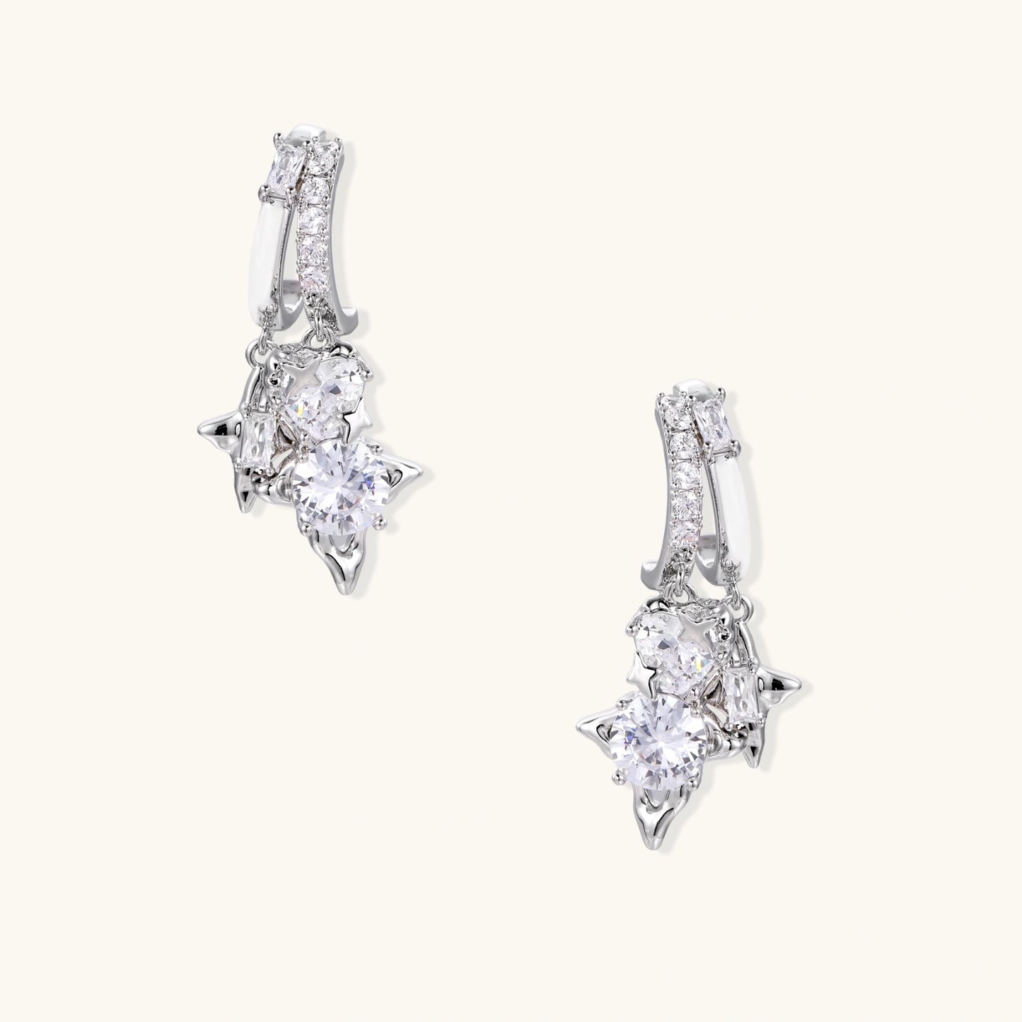 White gold-plated huggie earrings with geometric emerald-cut zirconia clusters in starburst formation on beige background