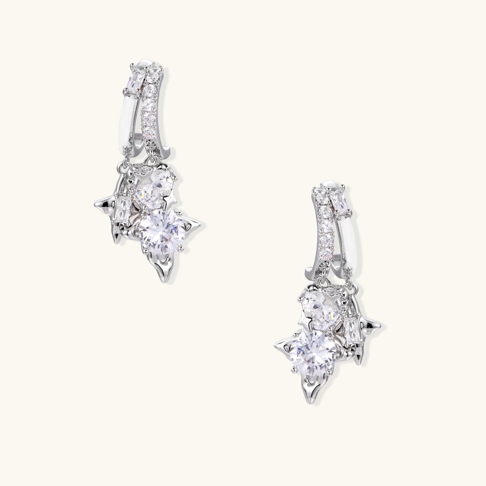 White gold-plated huggie earrings with geometric emerald-cut zirconia clusters in starburst formation on beige background