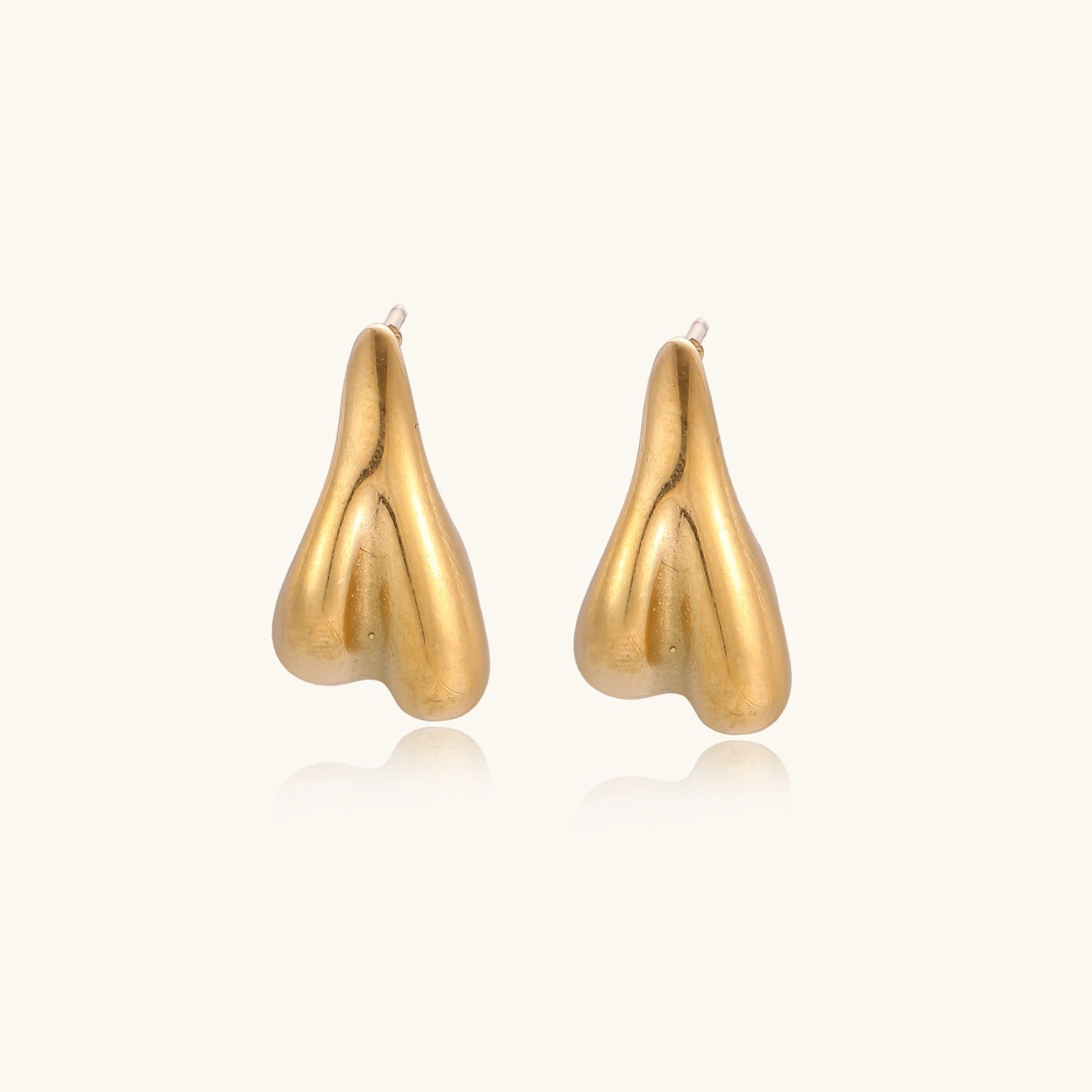 Organic sculptural gold stud earrings with fluid matte finish on cream background