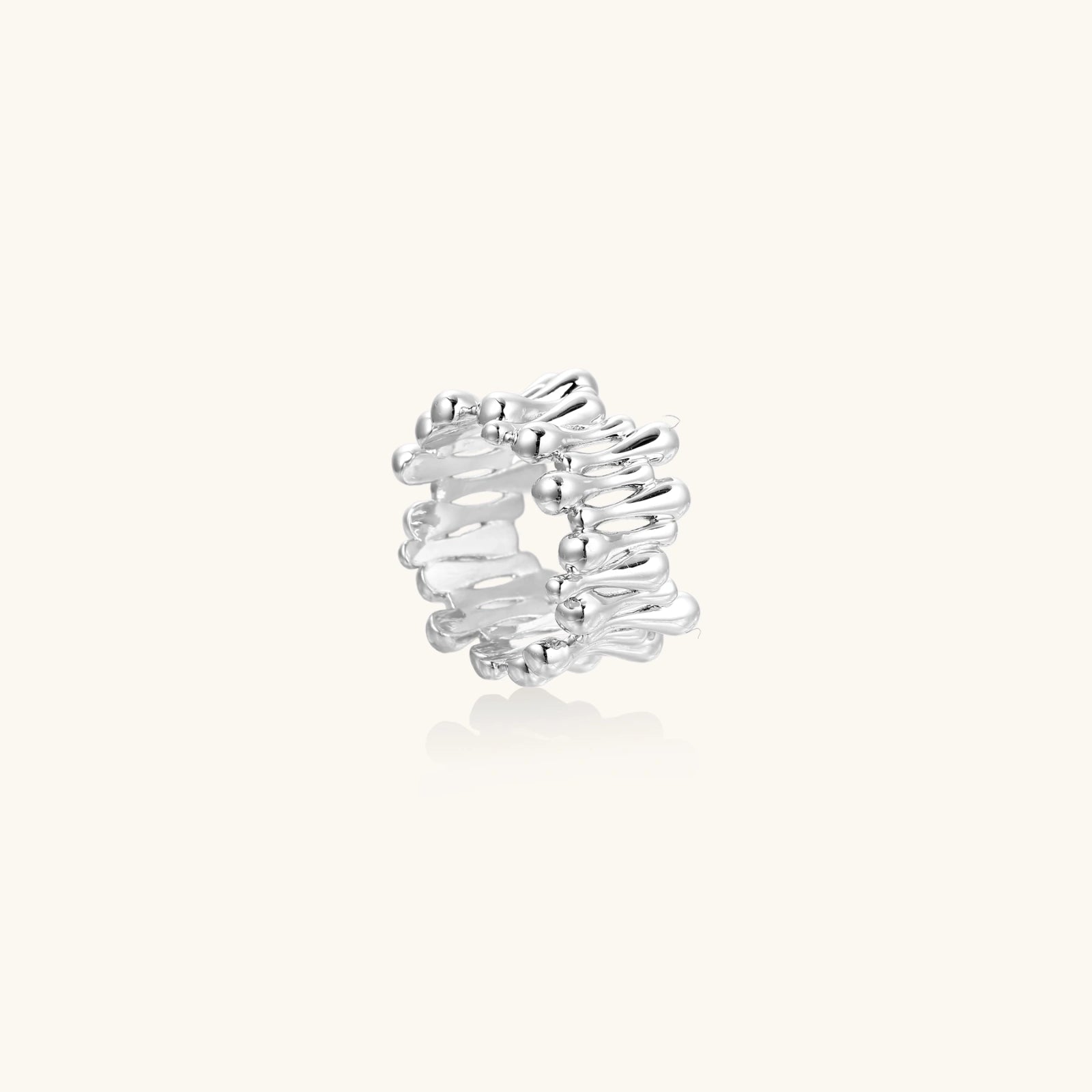 Wide band ring with sculptural wave ripples in polished white gold plated eco-brass on cream background
